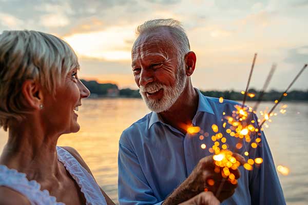 happy couple by the river with sparklers talking about retirement planning considerations